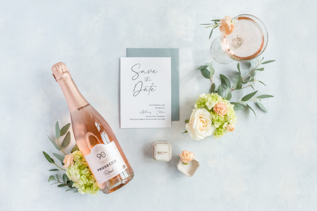 High end engagement photography featuring rose prosecco, a save the date and an engagement ring.
