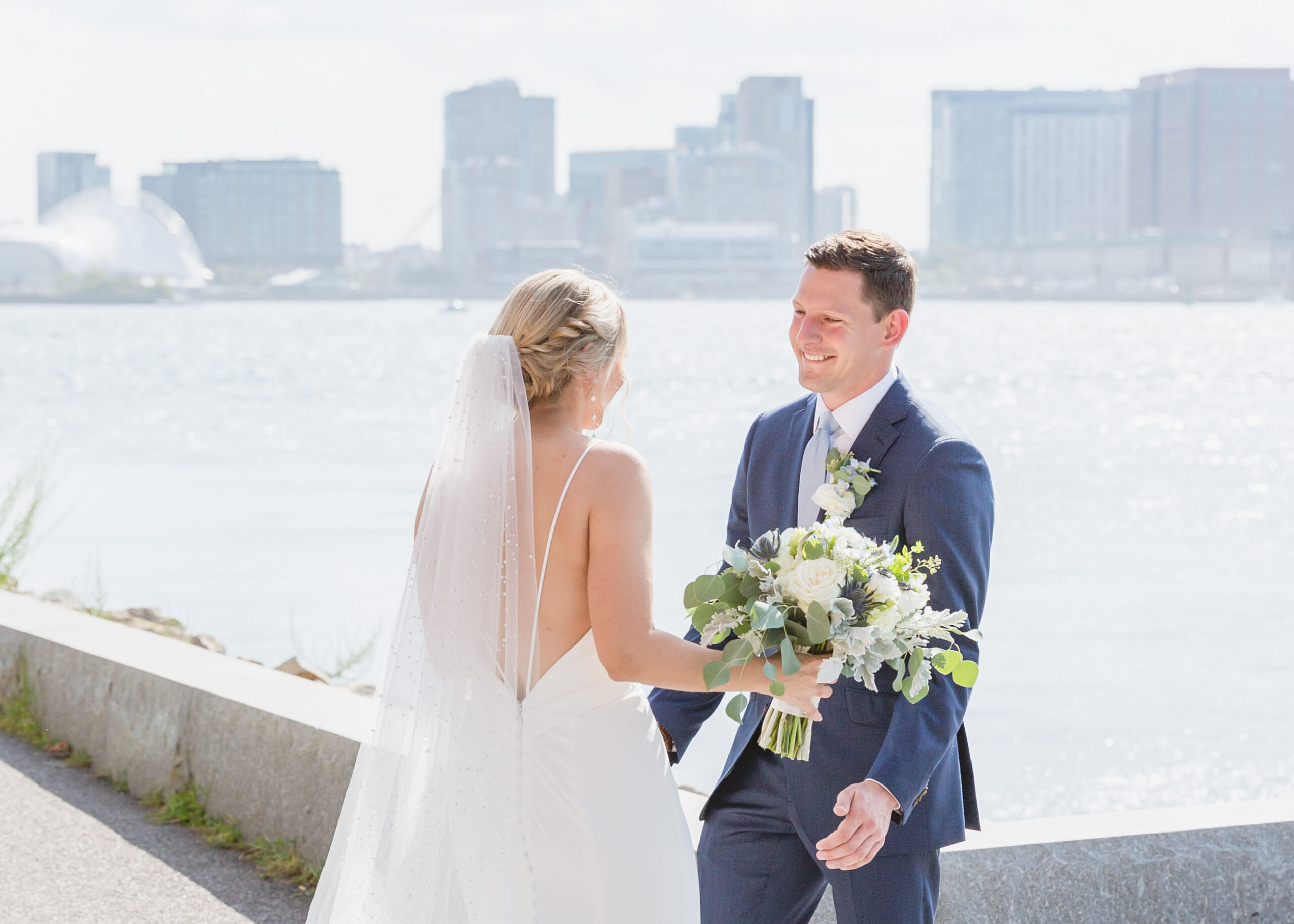 Couple shares a first look with the Boston skyline in the distance at the Hyatt Regency in Boston, Massachusetts.