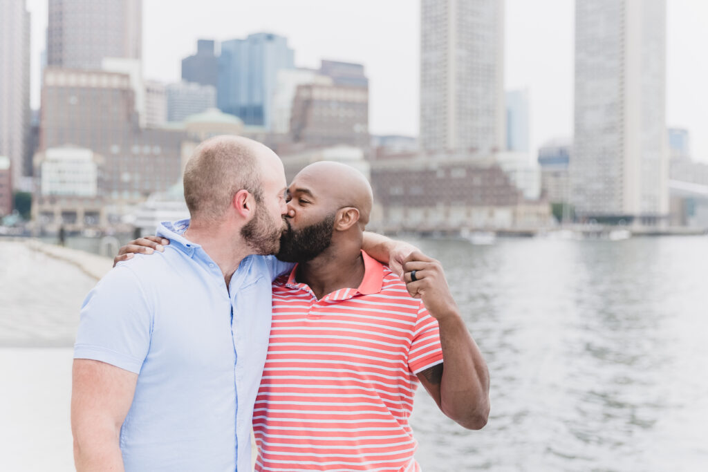 Gay couple kiss after getting engaged  at Fan Pier Park in Boston, MA.