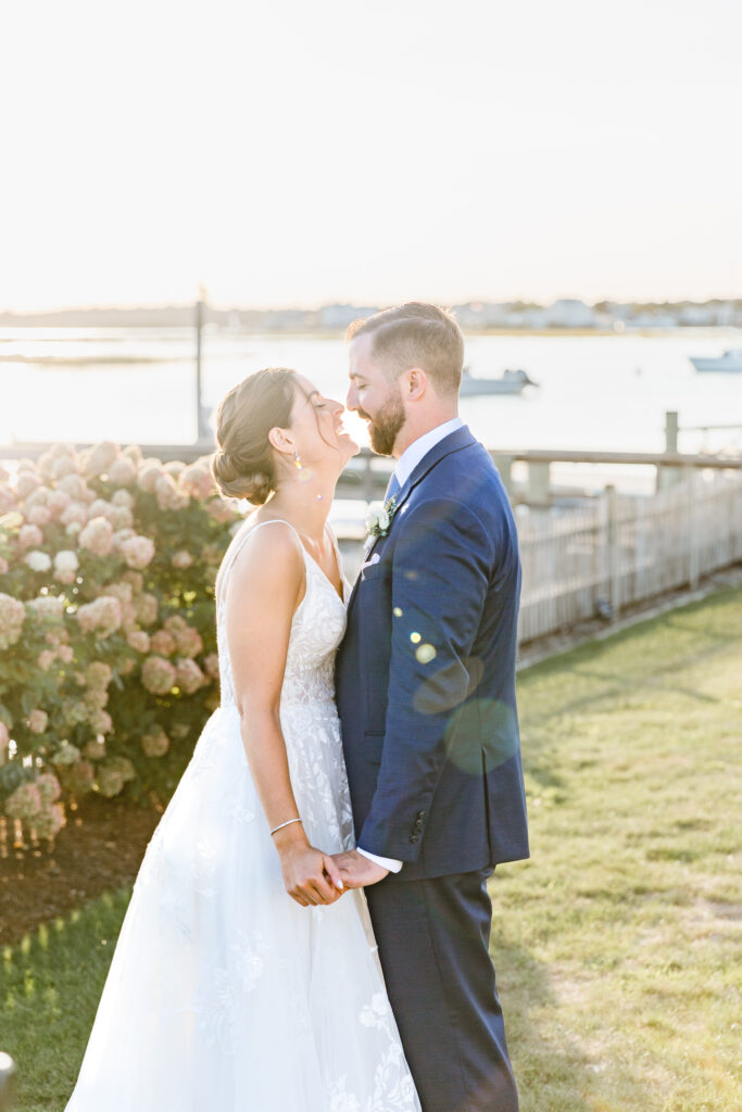 Bride and groom laugh and have a romantic moment at sunset at the West Dennis Yatch Club