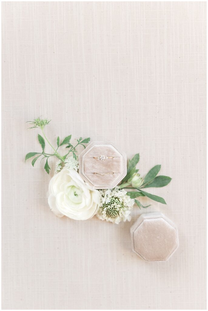 wedding and engagement rings from Laura Preshong on a soft linen background surrounded by white and green florals